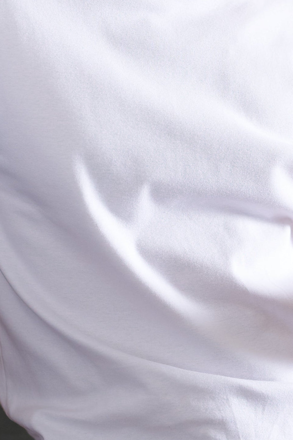 Man in white t-shirt and underwear holding a mug in a kitchen.